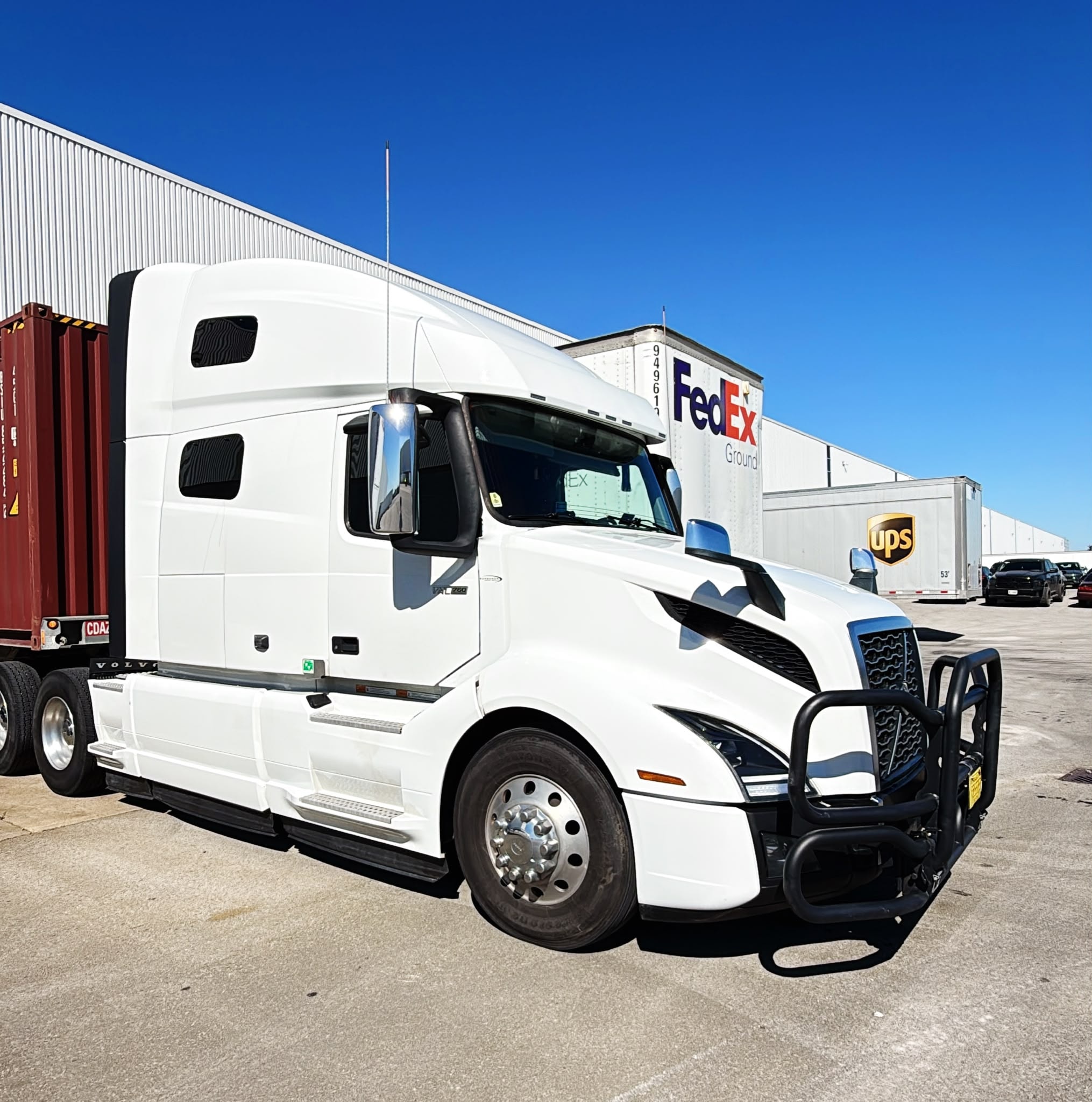 White Volvo truck at FedEx and UPS logistics facility